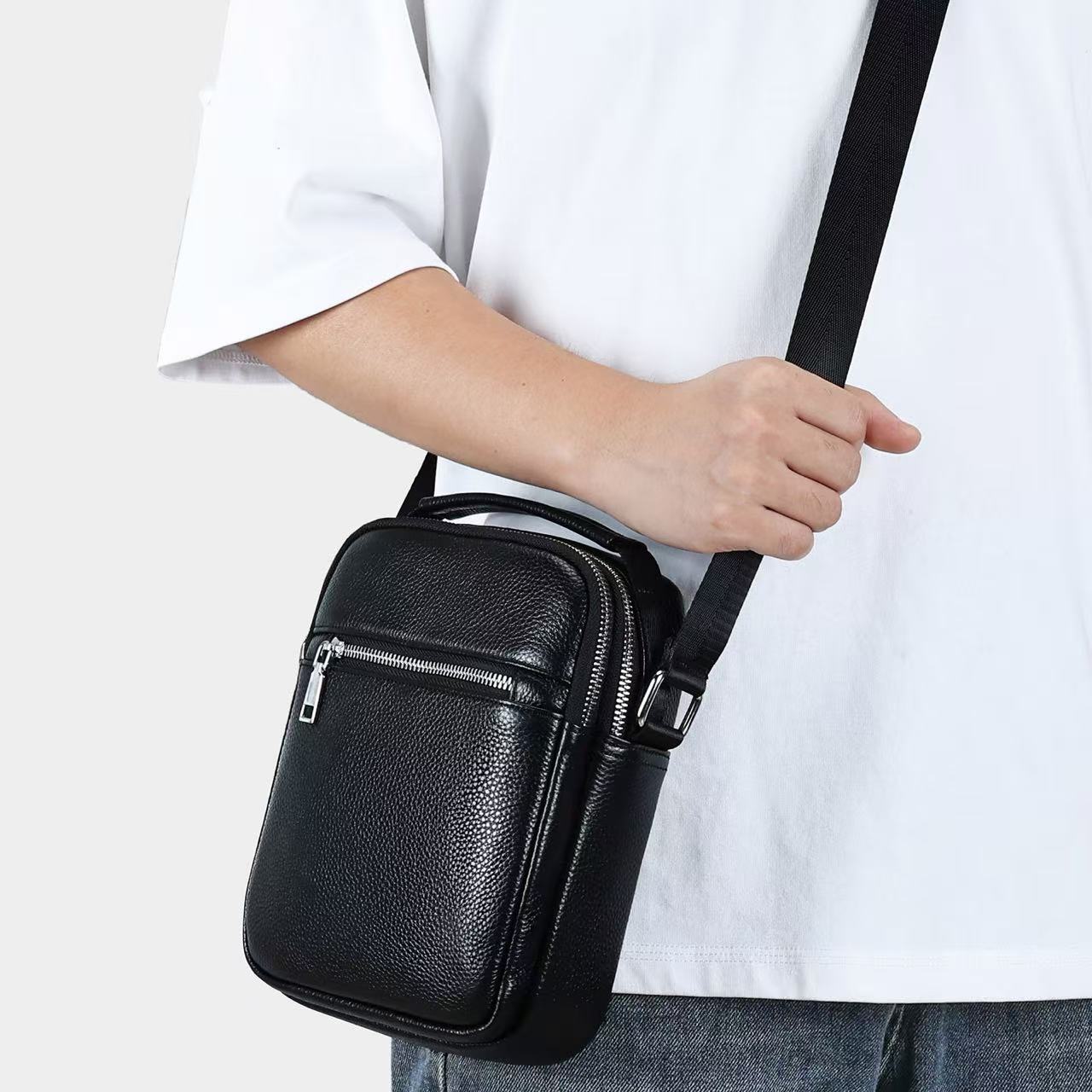 Black men's first layer cowhide crossbody bag by Golden Heir, showing front view with adjustable strap and compact design.