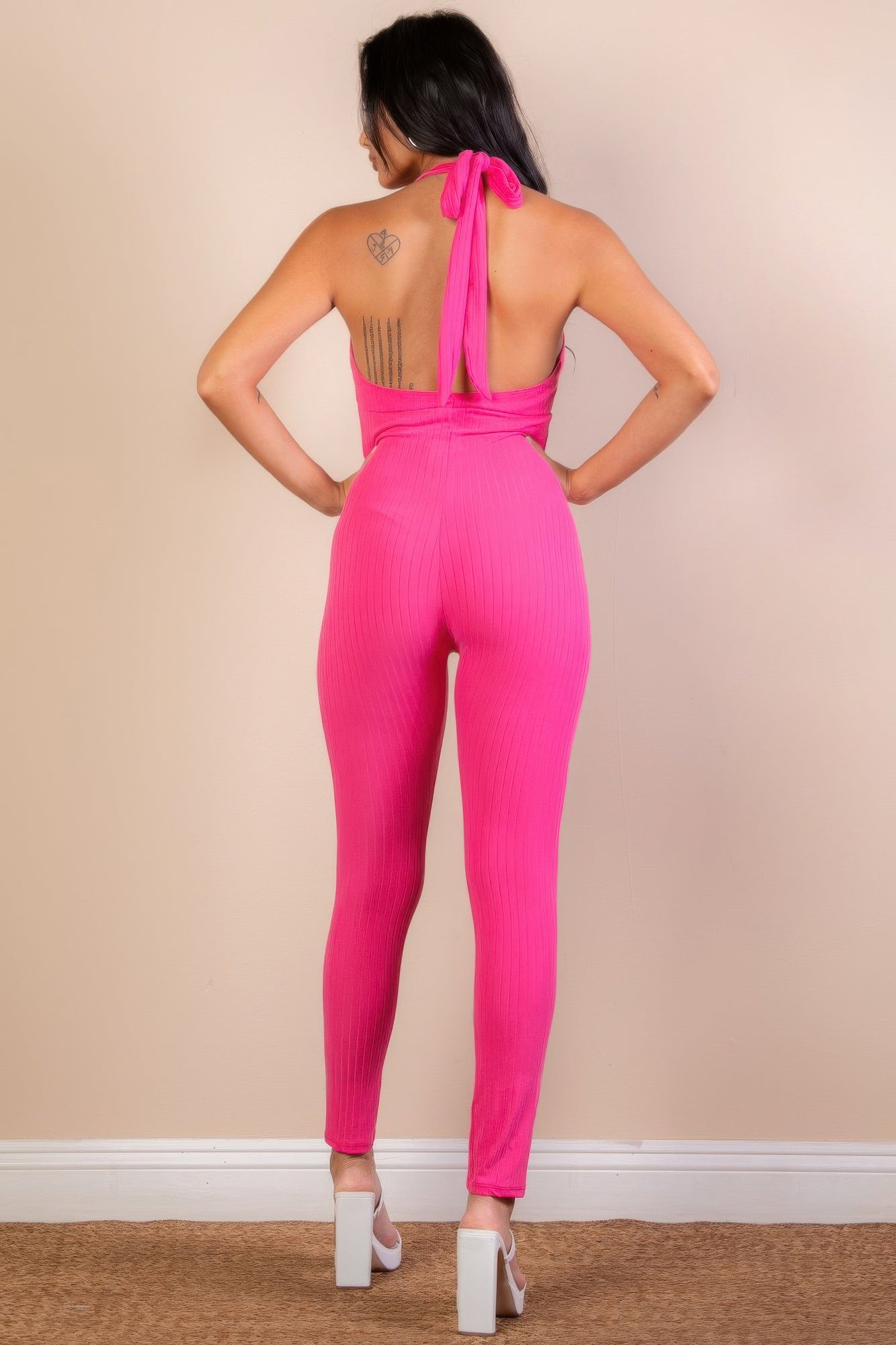 Golden Heir halter V-neck ribbed bodycon jumpsuit displayed on a model, showcasing its fitted silhouette and stylish design.